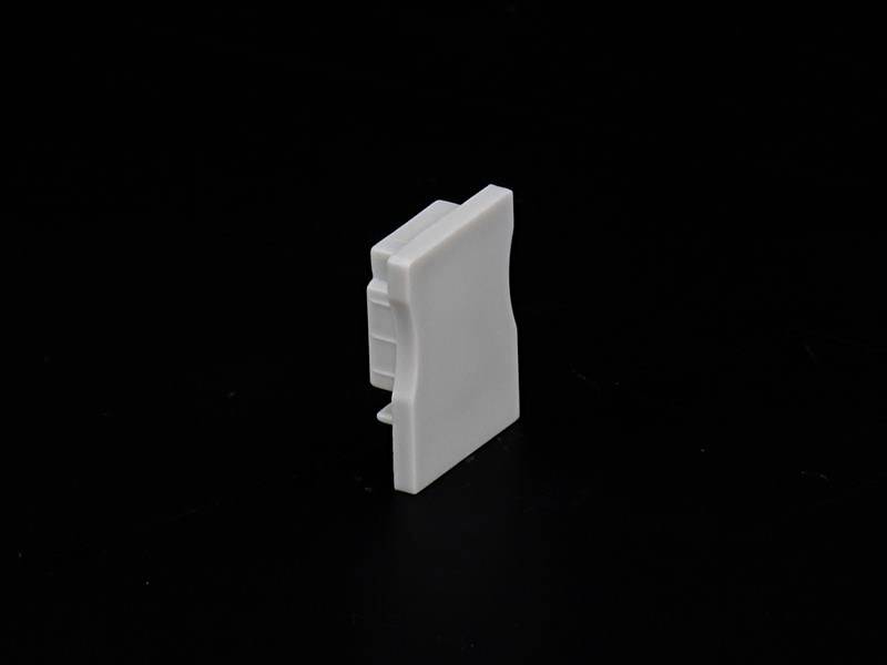 Weiße, rechteckige Kunststoffkomponente auf schwarzem Hintergrund.