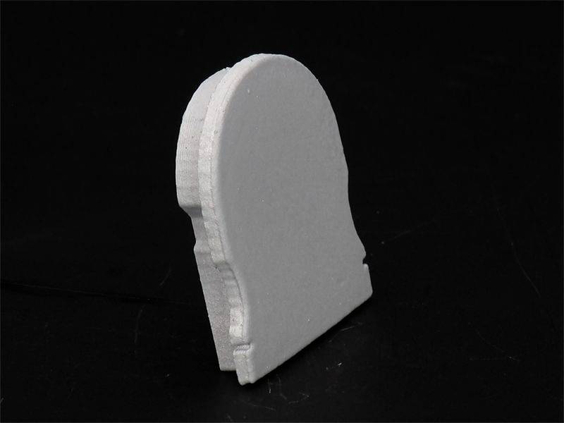 Einfacher, weißer Holzpuzzleteil auf schwarzem Hintergrund in Form eines unteren Segmentes eines menschlichen Kopfprofils.