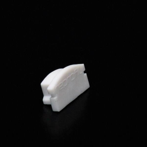 Ein kleiner, weißer Plastikgegenstand, auf schwarzem Hintergrund, trägt die Prägung 'EROI'. Rechteckige Form mit abgerundeten Kanten.