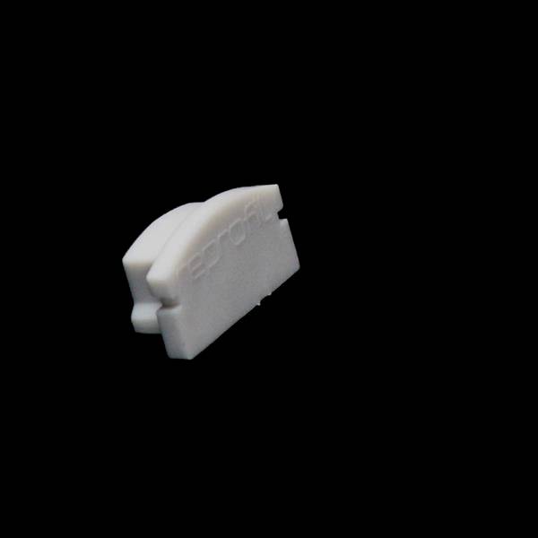 Ein weißes, gebogenes Objekt auf schwarzem Hintergrund, das wie ein kleiner Kunststoffclip aussieht.