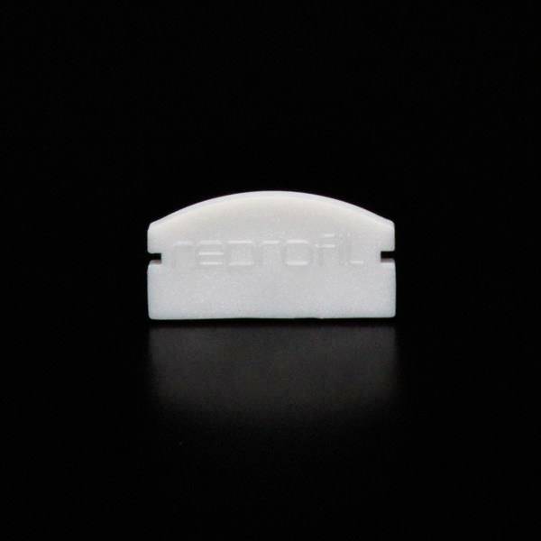 Ein kleines, weißes Plastikobjekt mit Aufschrift auf schwarzem Hintergrund.