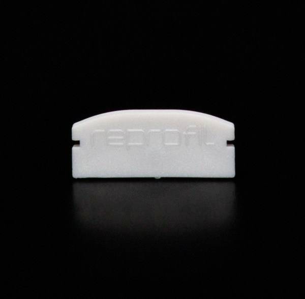 Ein kleines, weißes Kunststoffobjekt mit 'reprofil' darauf eingraviert, liegt auf einem schwarzen Hintergrund.