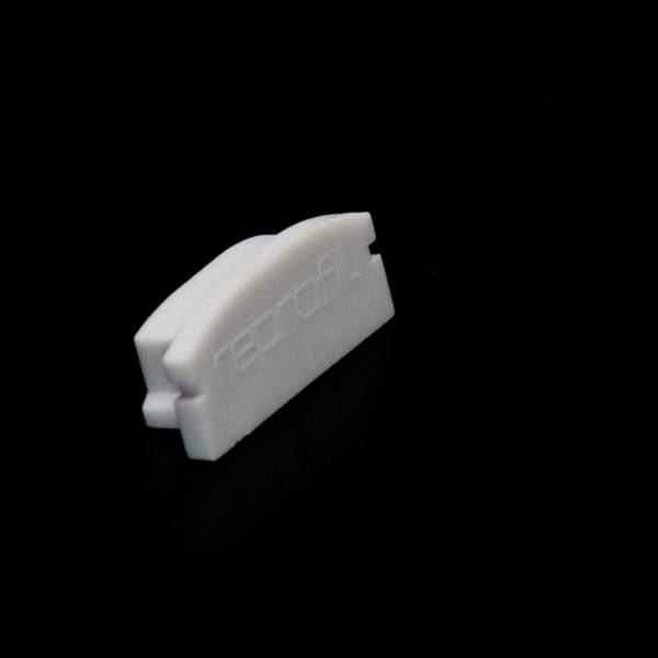 Ein kleines, weißes, halbkreisförmiges Objekt auf schwarzem Hintergrund, möglicherweise Kunststoff. Es trägt den Schriftzug 'record'.