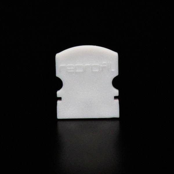 Eine weiße Kunststoffscheibe vor schwarzem Hintergrund. Sie hat eine gebogene Oberkante und zwei seitliche Einkerbungen.