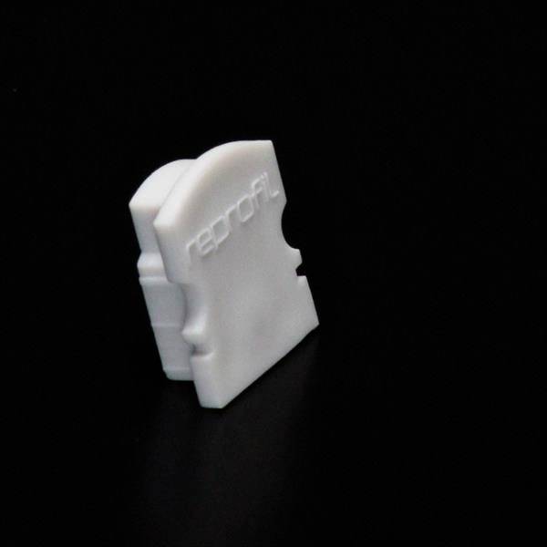 Ein weißer Kunststoffclip auf schwarzem Hintergrund, mit der Aufschrift 'profil'.