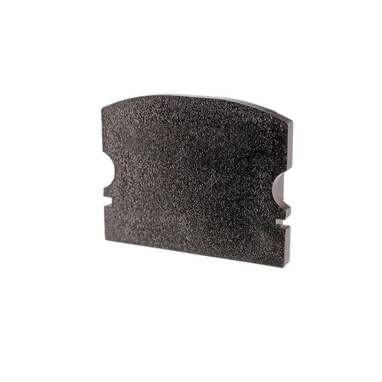 Bremsbelag in Nahaufnahme, abgerundetes Rechteck mit zwei Einkerbungen an den Seiten, zeigt texturierte Oberfläche.