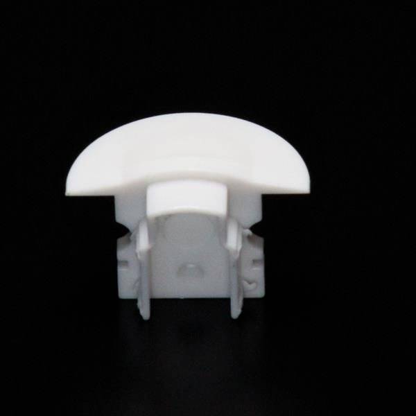 Weiße abgerundete Kunststoffkappe auf schwarzem Hintergrund, möglicherweise Teil eines Möbelstücks oder Gehäuses.