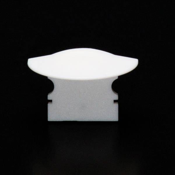 Ein weißes Plastikteilstück vor einem schwarzen Hintergrund, etwa in Form eines stilisierten Vogels mit ausgebreiteten Flügeln.