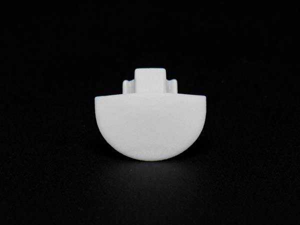 Ein einzelner weißer Kunststoffknopf vor schwarzem Hintergrund.