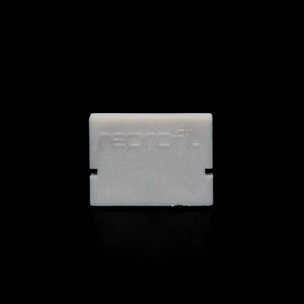 Ein rechteckiges, weißes Objekt mit dem eingeprägten Schriftzug 'reprofit' auf schwarzem Hintergrund.