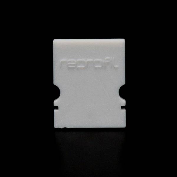 Ein weißes Kunststoffteil auf schwarzem Hintergrund, auf dem das Wort 'reprofit' geprägt ist. Rechteckige Form mit zwei symmetrischen Seitenausschnitten.