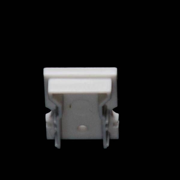 Ein weißer Kunststoffclip vor schwarzem Hintergrund, möglicherweise ein Befestigungsclip oder Halterung für Kabel oder kleine Gegenstände.
