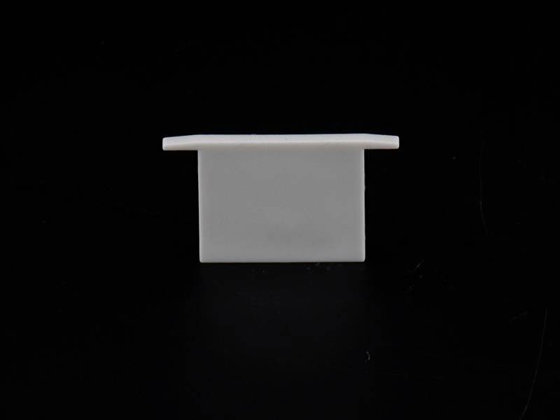 Ein weißes, rechteckiges Objekt steht vertikal auf einer schwarzen Oberfläche. Der Hintergrund ist komplett schwarz.