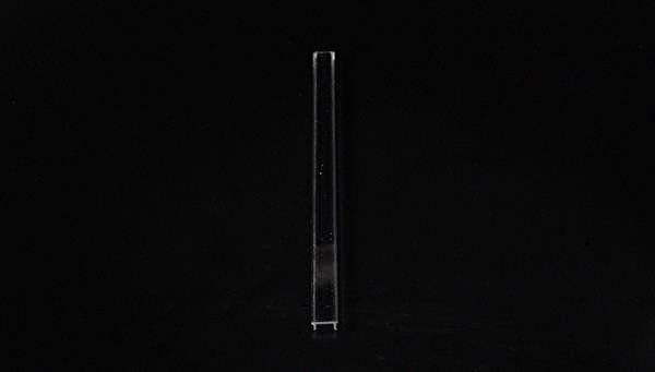 Ein schlichtes, transparentes Objekt auf schwarzem Hintergrund. Das Objekt ist vertikal ausgerichtet und zylindrisch.