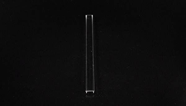 Ein einzelner transparenter Plastiktrinkhalm auf schwarzem Hintergrund, vertikal ausgerichtet.