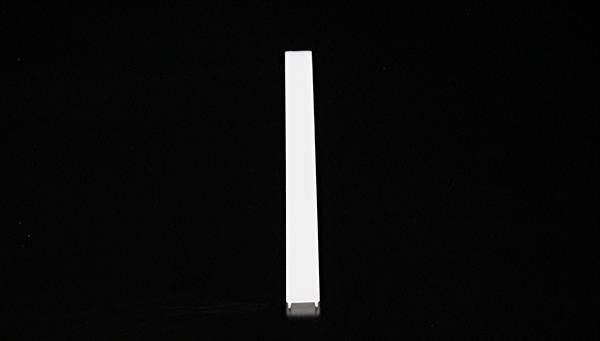 Ein einzelner, weißer, länglicher Gegenstand liegt in der Mitte eines schwarzen Hintergrunds.