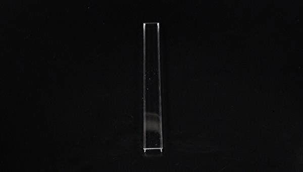 Ein einzelner, transparenter Rechteckstab steht aufrecht vor einem schwarzen Hintergrund.