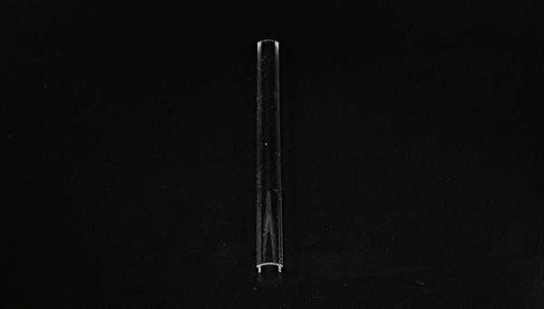 Ein transparenter Glasstab steht vertikal auf einem schwarzen Hintergrund.