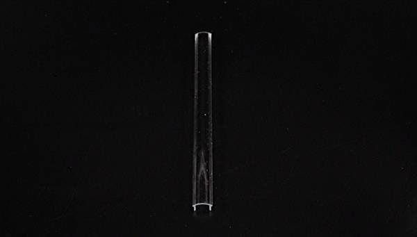 Ein einzelnes durchsichtiges Reagenzglas steht vertikal auf schwarzem Hintergrund.