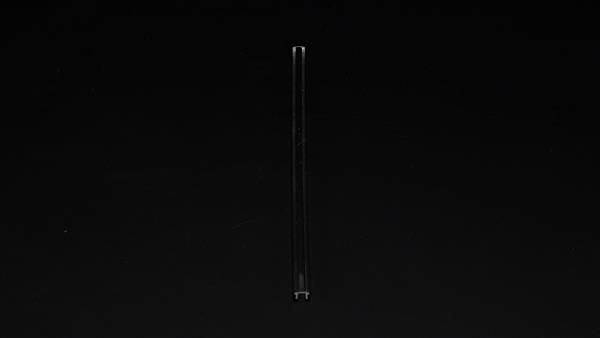 Ein einzelner, dünner Stab steht vertikal auf einem schwarzen Hintergrund.