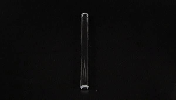 Ein transparentes Reagenzglas liegt horizontal auf schwarzem Hintergrund.