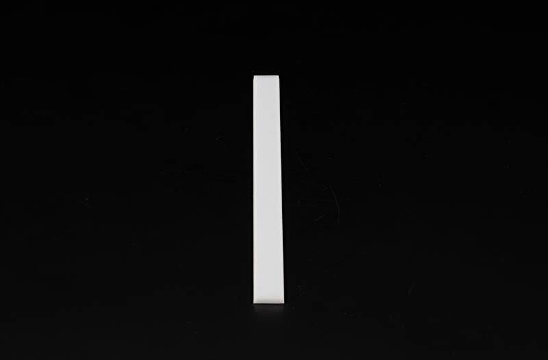 Weißer, rechteckiger Ziegelstein, vertikal auf schwarzem Hintergrund positioniert. Minimalistisches Design mit hohem Kontrast.