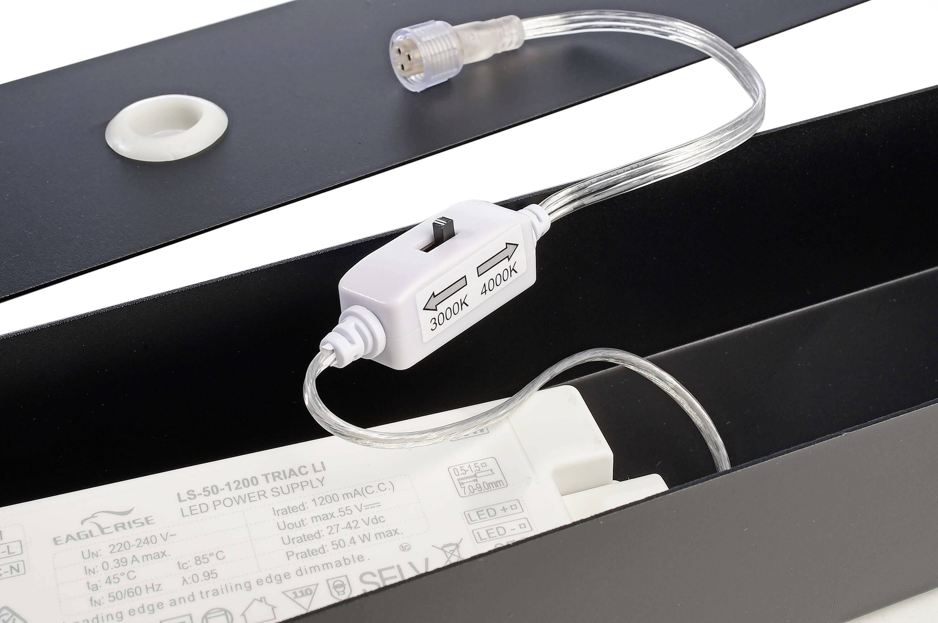 Stecker mit Schalter zwischen 3000K und 4000K für LED-Leuchten, beige Kabel. Hintergrund zeigt Teile von LED-Leuchten.