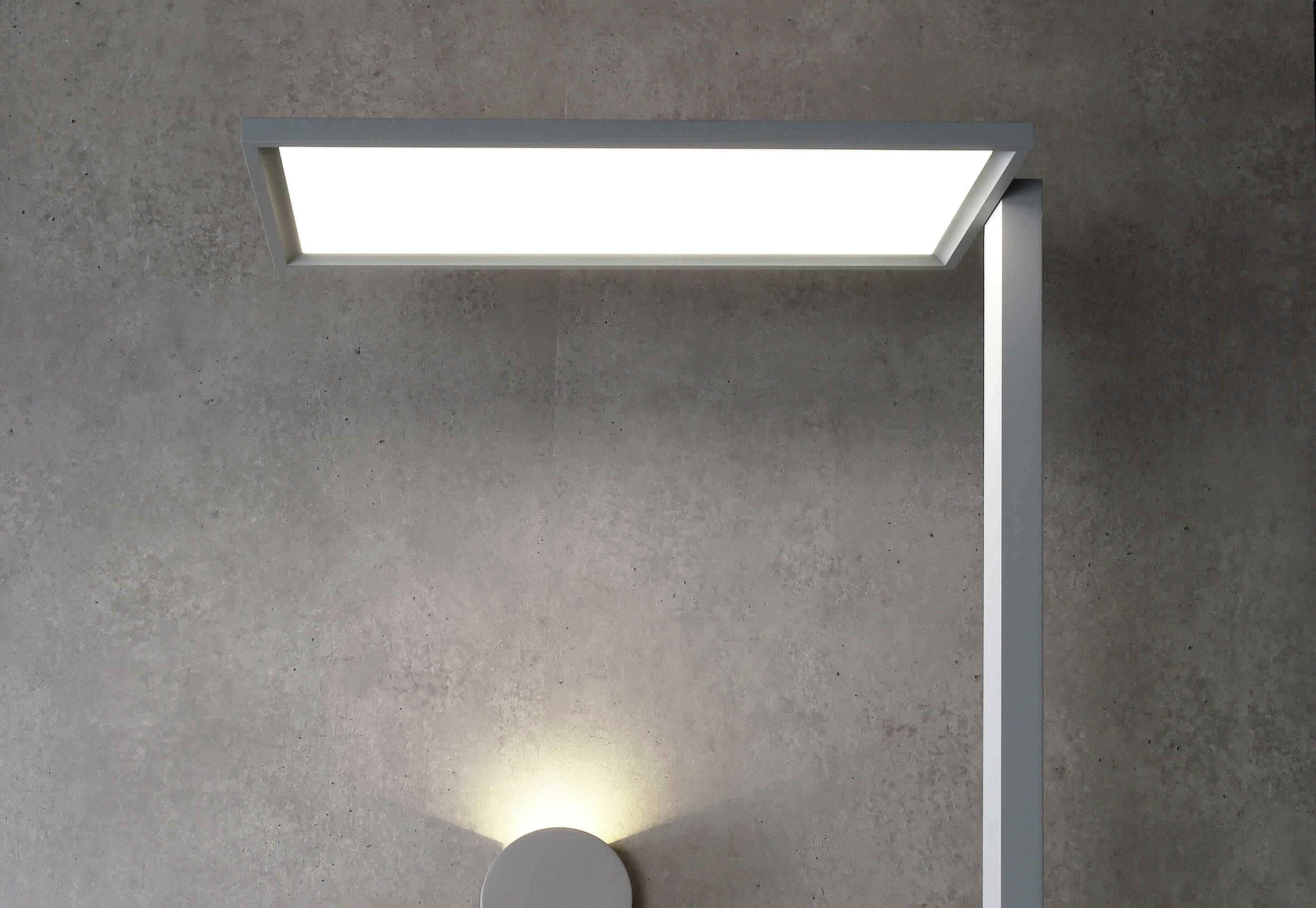 Eine moderne, minimalistische Wandleuchte aus Metall mit rechteckigem Lampenschirm, die an einer grauen Betonwand befestigt ist.