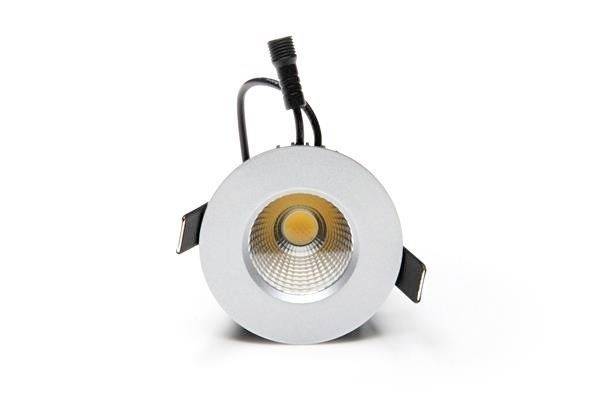 Ein runder Einbaustrahler mit silbernem Gehäuse und einem orangefarbenen LED-Licht in der Mitte. Ein Kabel ragt nach hinten heraus.