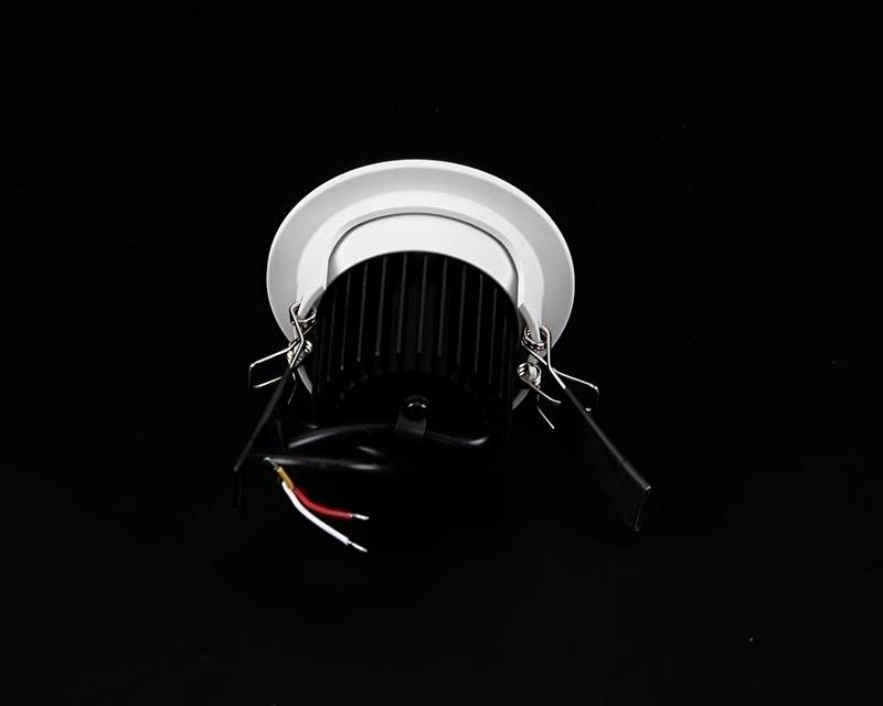 Runder LED-Einbaustrahler mit schwarzem Kühlkörper und sichtbaren Kabeln, auf schwarzem Hintergrund platziert.