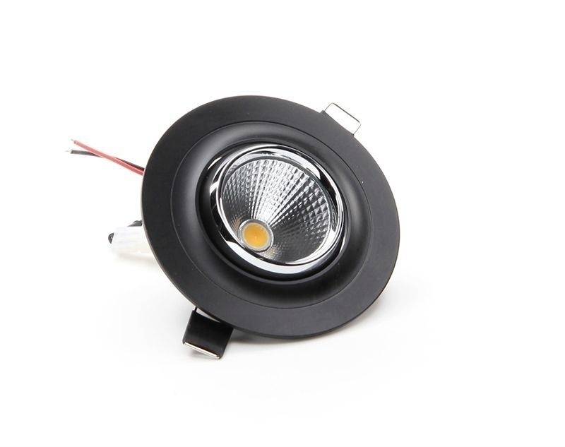 Ein runder, schwarzer LED-Strahler mit silberner Fassung und herausragenden Kabeln liegt auf einer weißen Oberfläche.