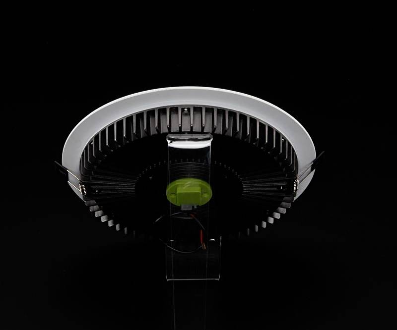 Unteransicht einer runden LED-Lampe mit schwarzem Kühlkörper und weißem Rand auf schwarzem Hintergrund.