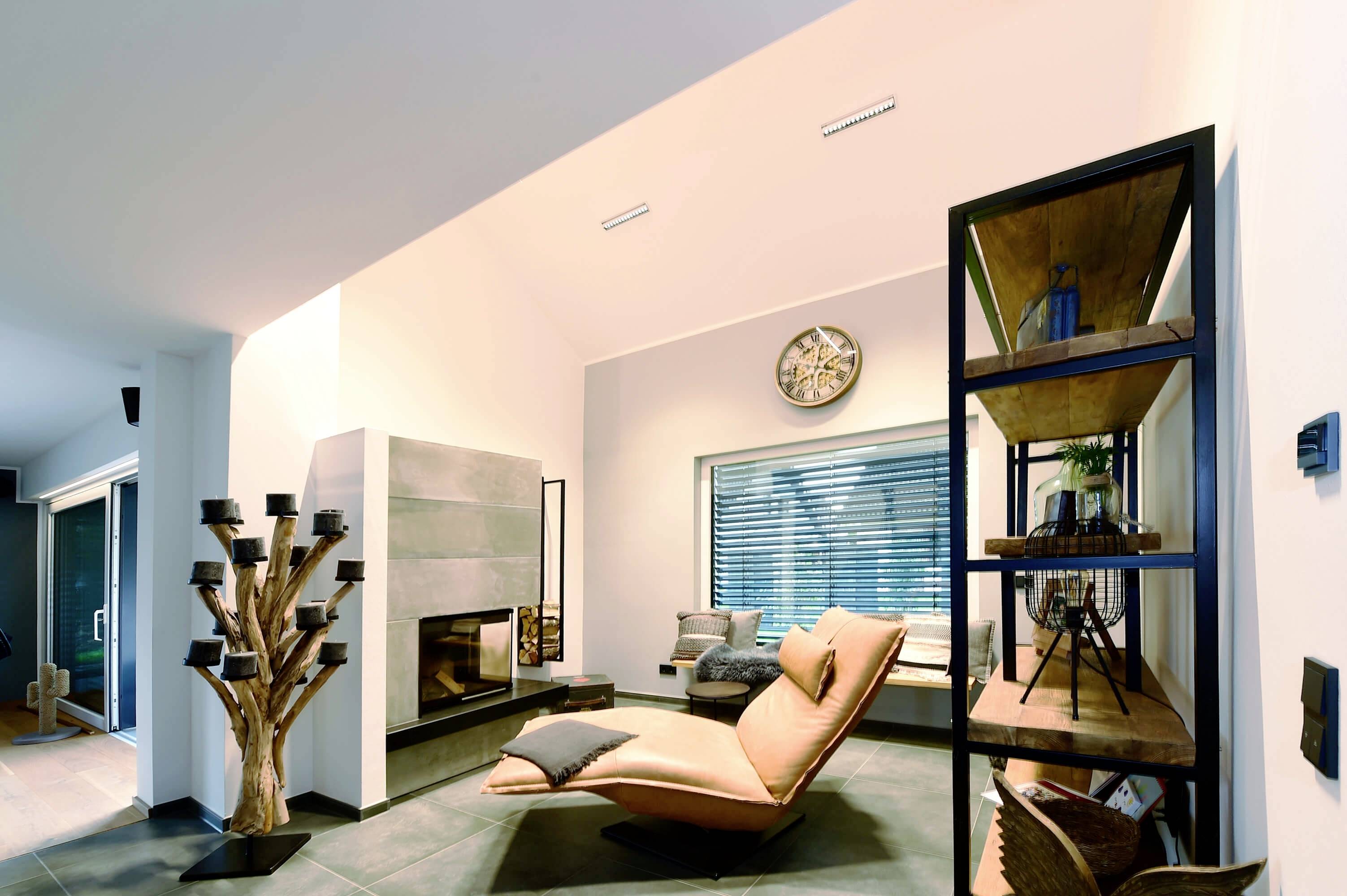 Ein modern eingerichtetes Wohnzimmer mit einem Liegesessel, einem Bücherregal, einem Kamin und einer großen Uhr an der Wand.