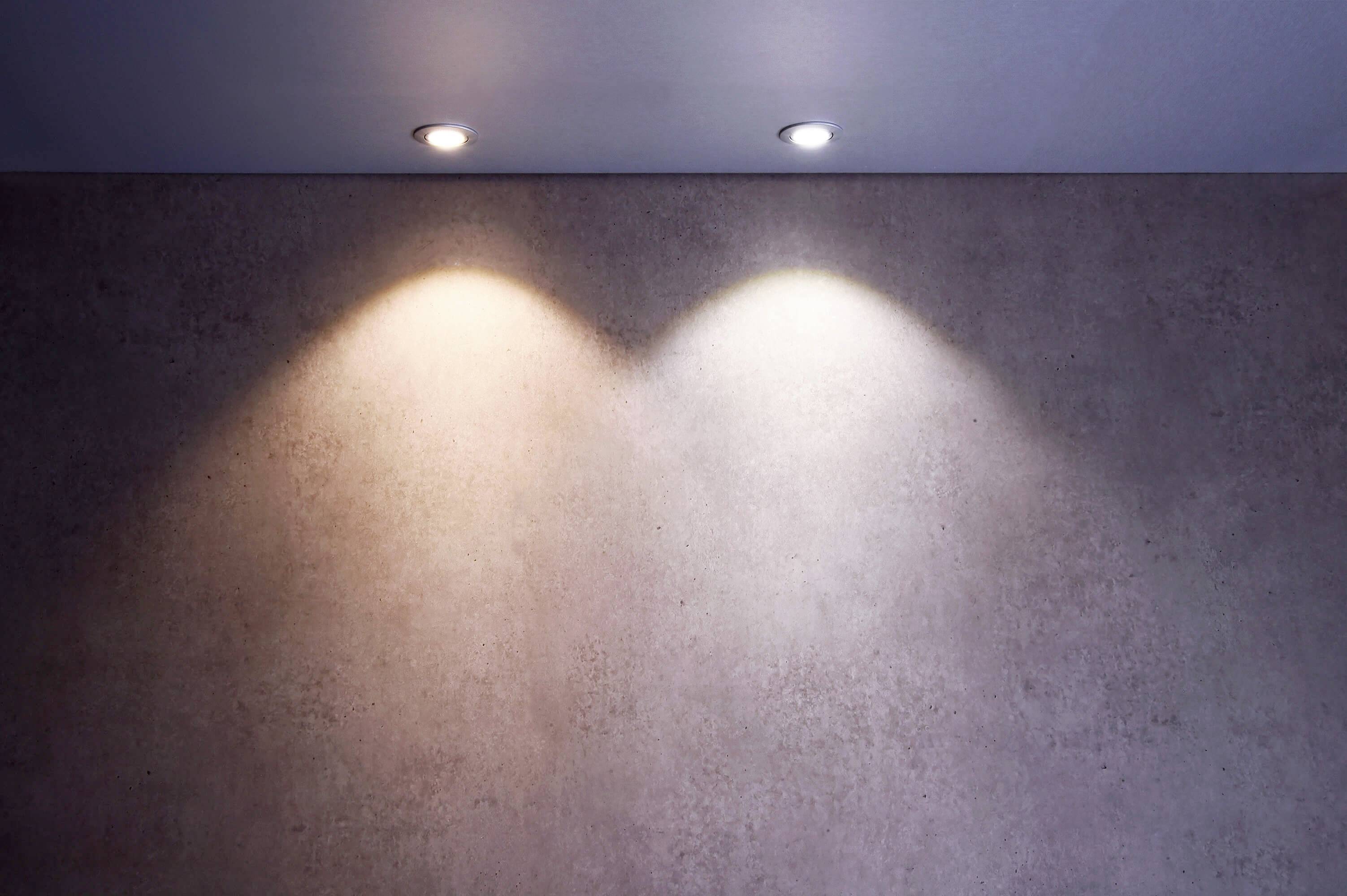 Zwei Spotlichter beleuchten die Wand unterschiedlich: links warmes, rechts kaltes Licht. Beleuchtungstechnik wird dargestellt.
