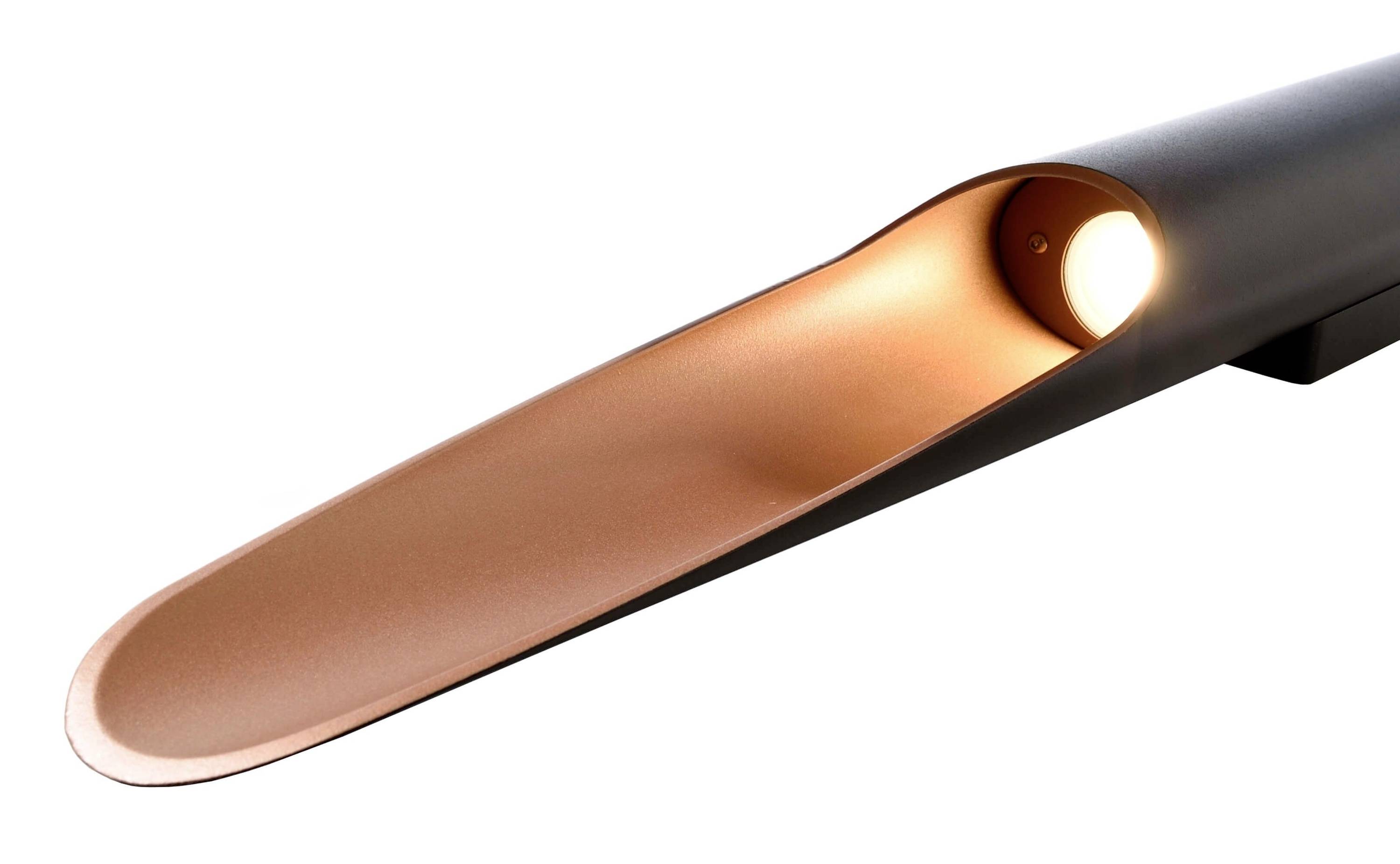 Eine moderne Wandlampe mit einem metallischen, kupferfarbenen Inneren und einem schlanken, schwarzen äußeren Gehäuse, beleuchtet aus einem Punkt.