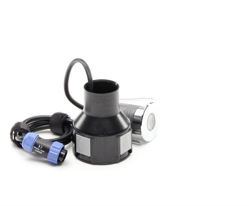 Ein schwarzer zylindrischer Adapter mit Kabel und blauer Steckverbindung. Im Hintergrund ein silbernes Gerät mit rundem Display.