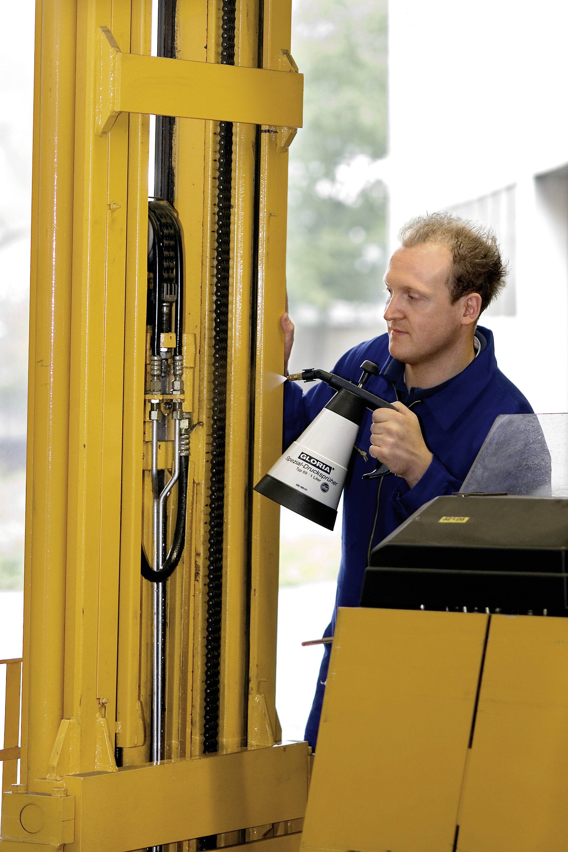 Ein Mann in Arbeitskleidung inspiziert einen gelben Gabelstaplermechanismus und hält eine Lampe für bessere Sicht.
