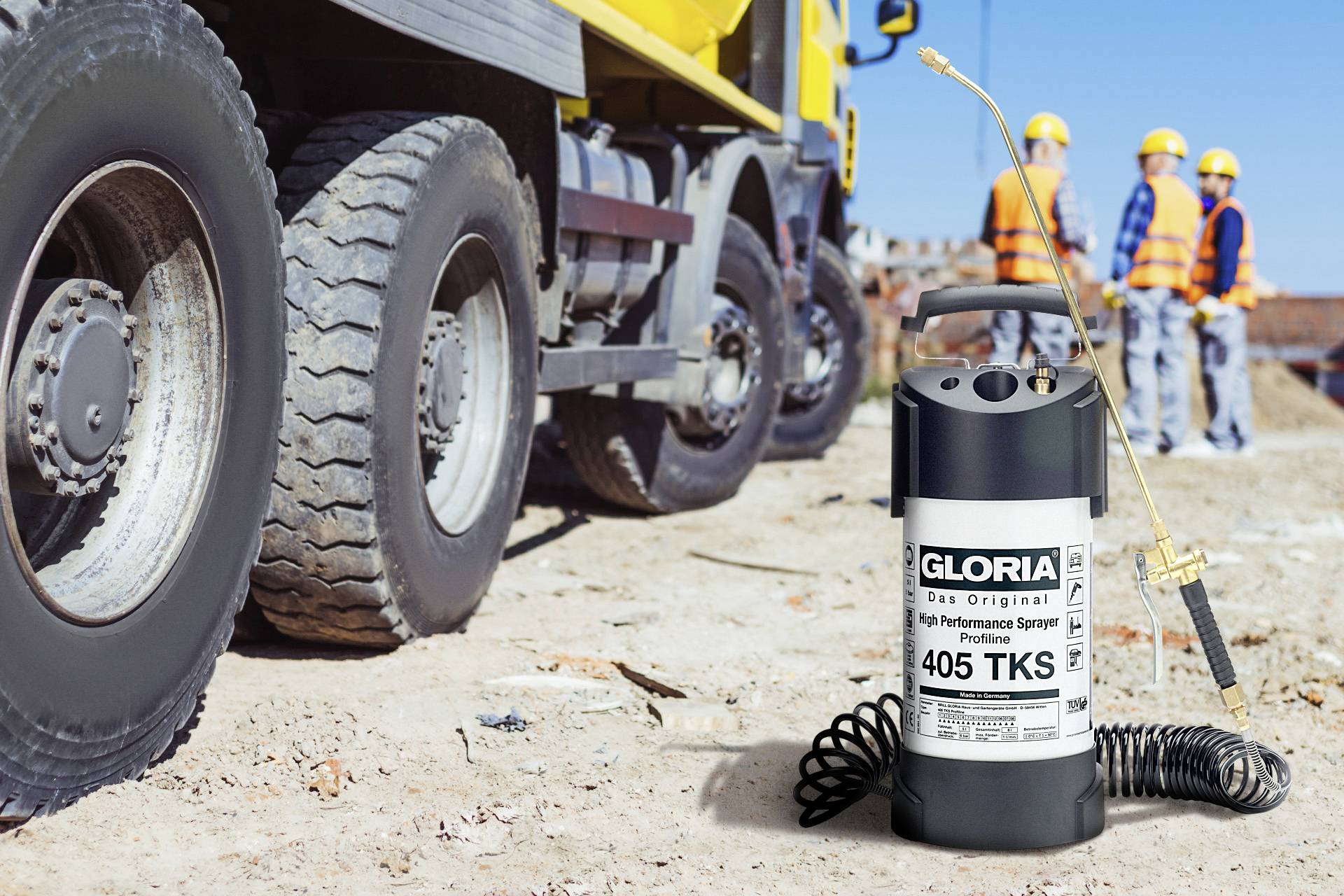 Bauarbeiter stehen neben einem Baufahrzeug auf einer Baustelle. Im Vordergrund ist ein Gloria Hochleistungssprüher zu sehen.