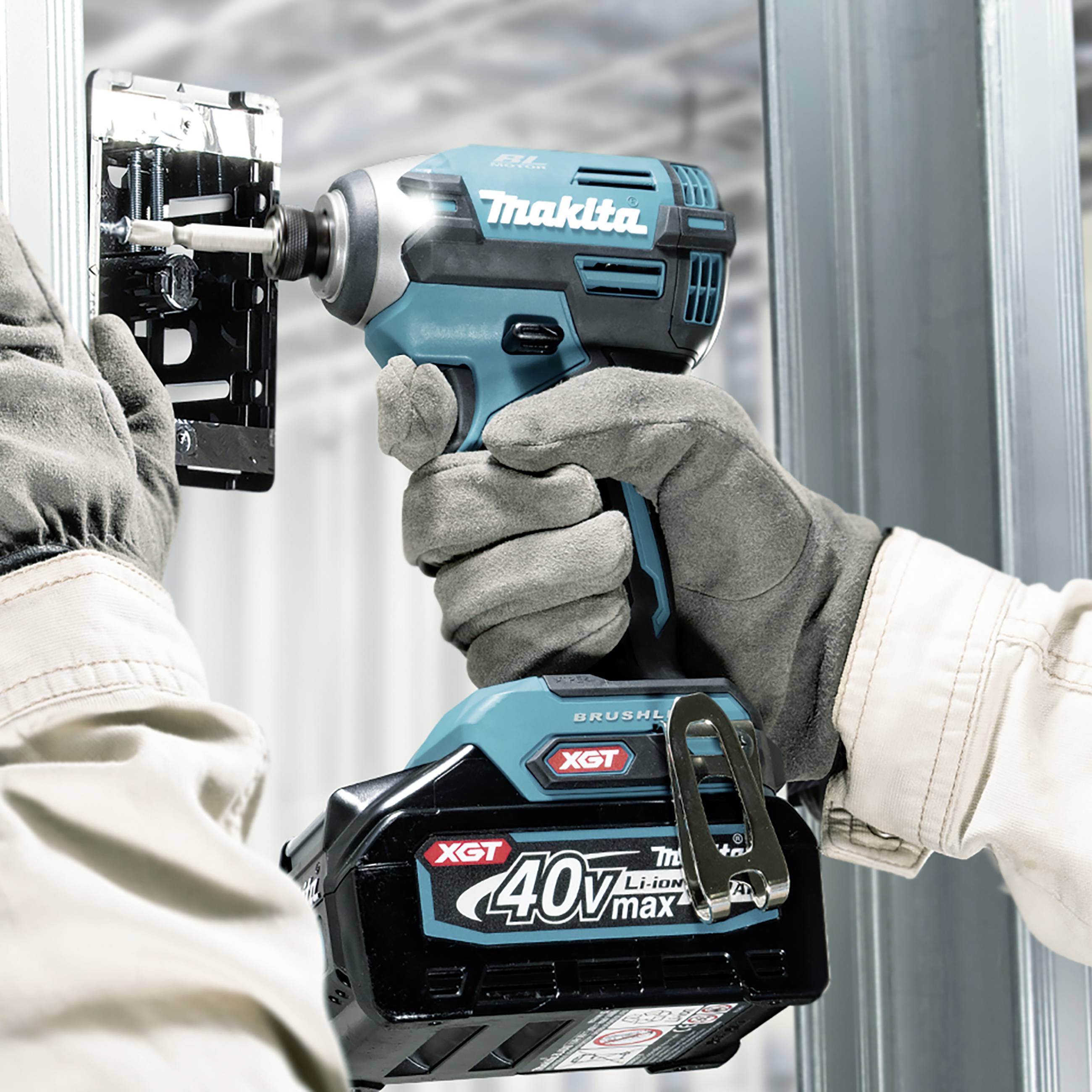 Eine Person montiert eine Metallkonstruktion mit einem blauen Akkuschrauber in einer industriellen Umgebung.