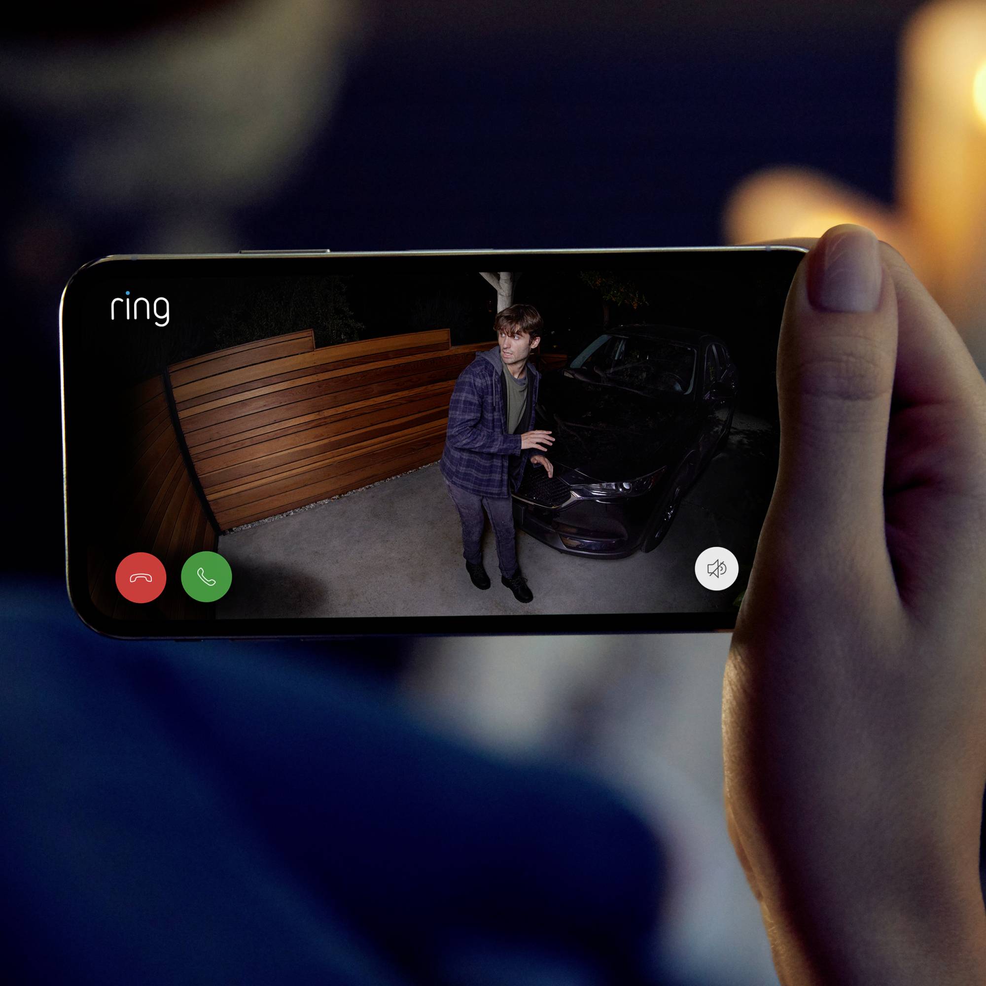 Eine Person wird auf einem Smartphone-Display gezeigt, während sie sich einem Auto in einer dunklen Umgebung nähert.