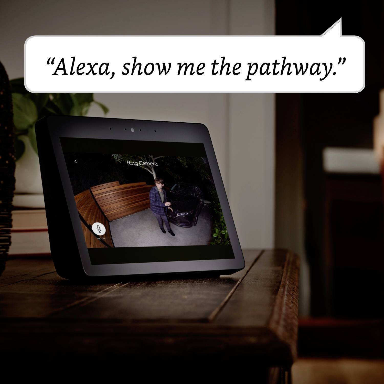 Ein Smart-Display zeigt eine Kameraaufnahme eines Mannes auf einer Einfahrt. Oben steht: 'Alexa, zeig mir den Weg.'