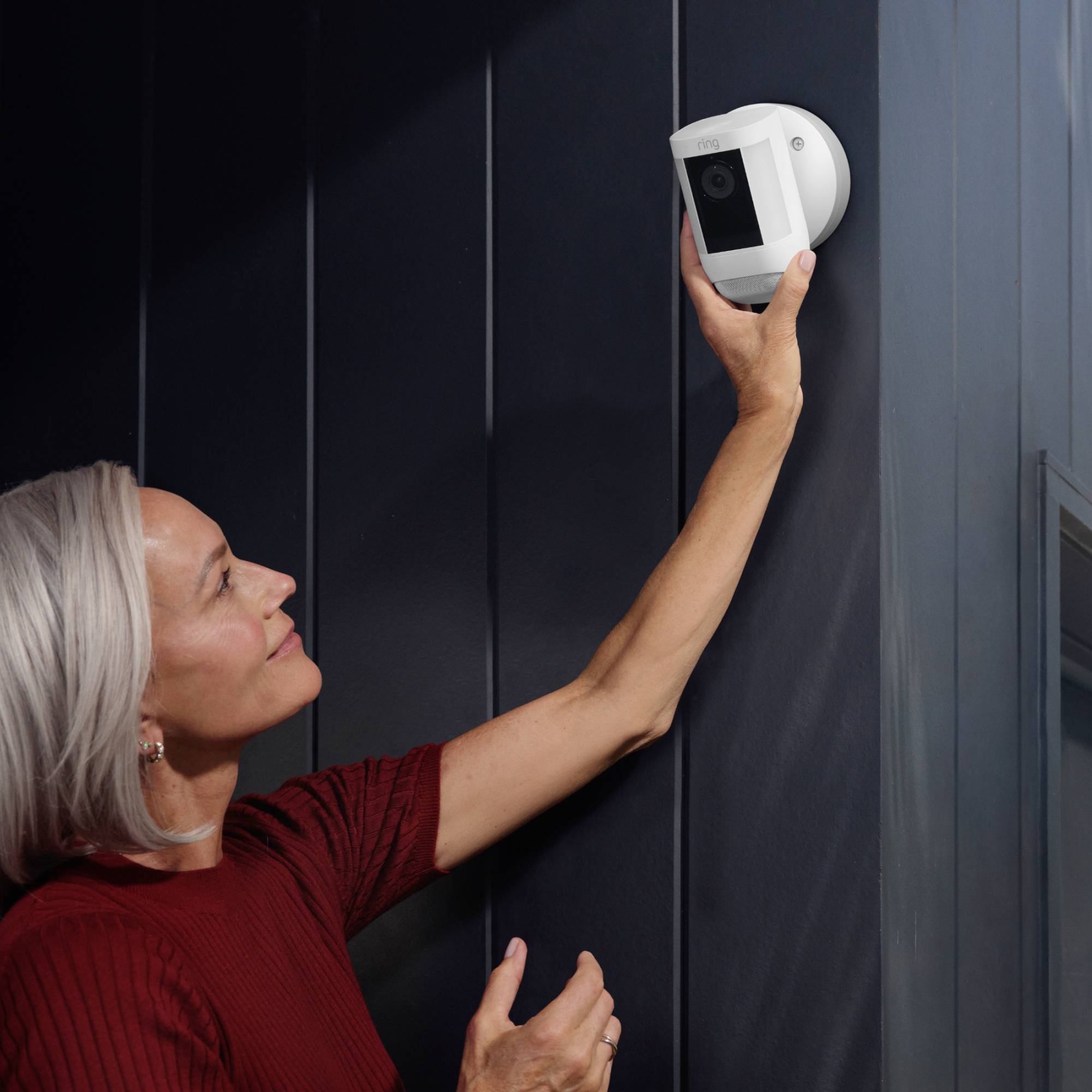 Eine Frau montiert eine Sicherheitskamera an eine Wand.