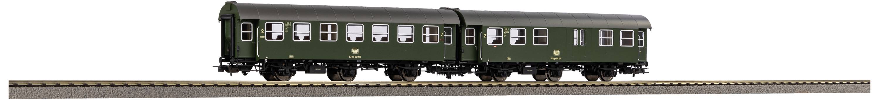 Ein grüner Eisenbahnzug mit zwei Wagen fährt auf einem Gleis. Die Wagen sind klassisch gestaltet mit weißen Fenstern.