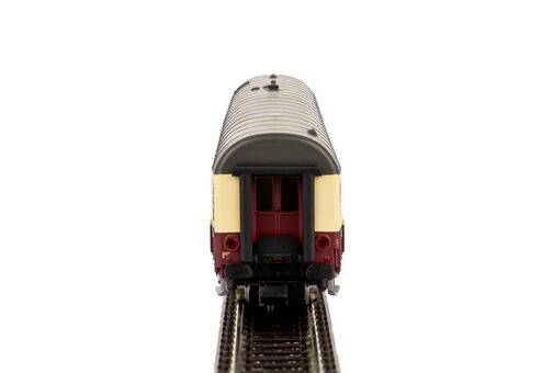 Ein detailliertes Modell eines roten und cremefarbenen Zugkabooses auf schmalen Eisenbahnschienen, von hinten betrachtet.