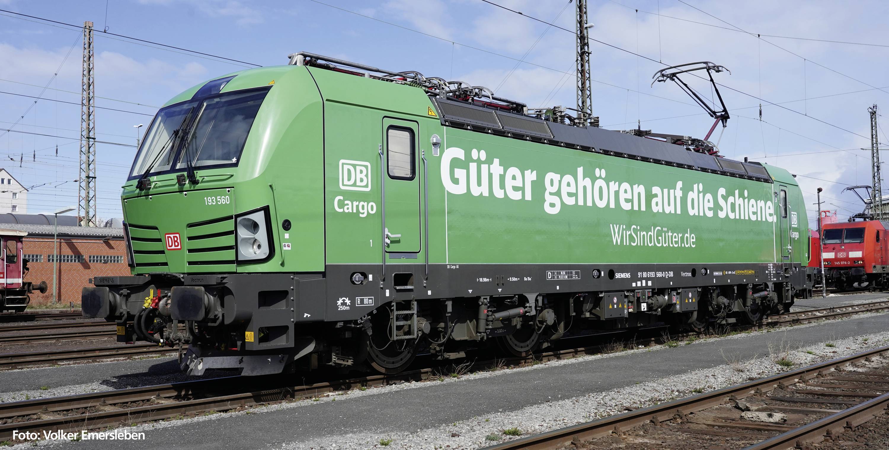 Grüner Güterzug der DB Cargo mit Aufschrift 'Güter gehören auf die Schiene' auf einem Bahnhofsgleis. Lokomotive im Vordergrund.