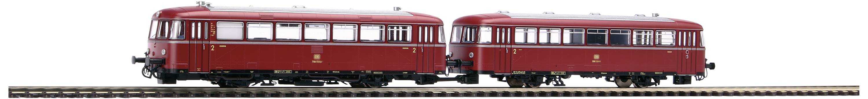 Ein roter Modellzug mit zwei Wagons auf einem Schienenstück. Er hat weiße Fenster und steht vor einem neutralen Hintergrund.