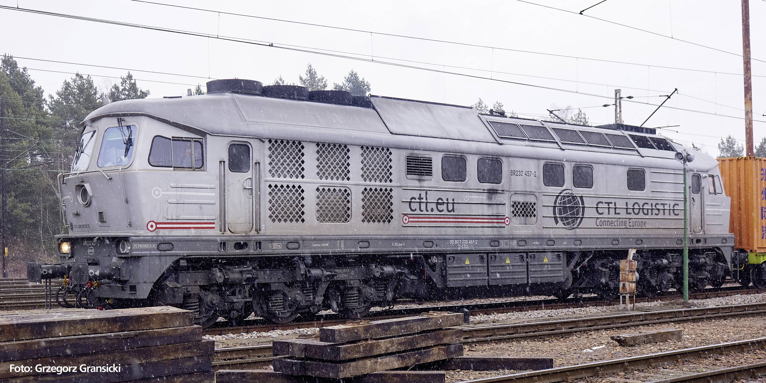 Ein silberfarbener Güterzug der CTL Logistics steht auf einem Bahngleis im Freien. Es ist bewölkt und es regnet leicht.