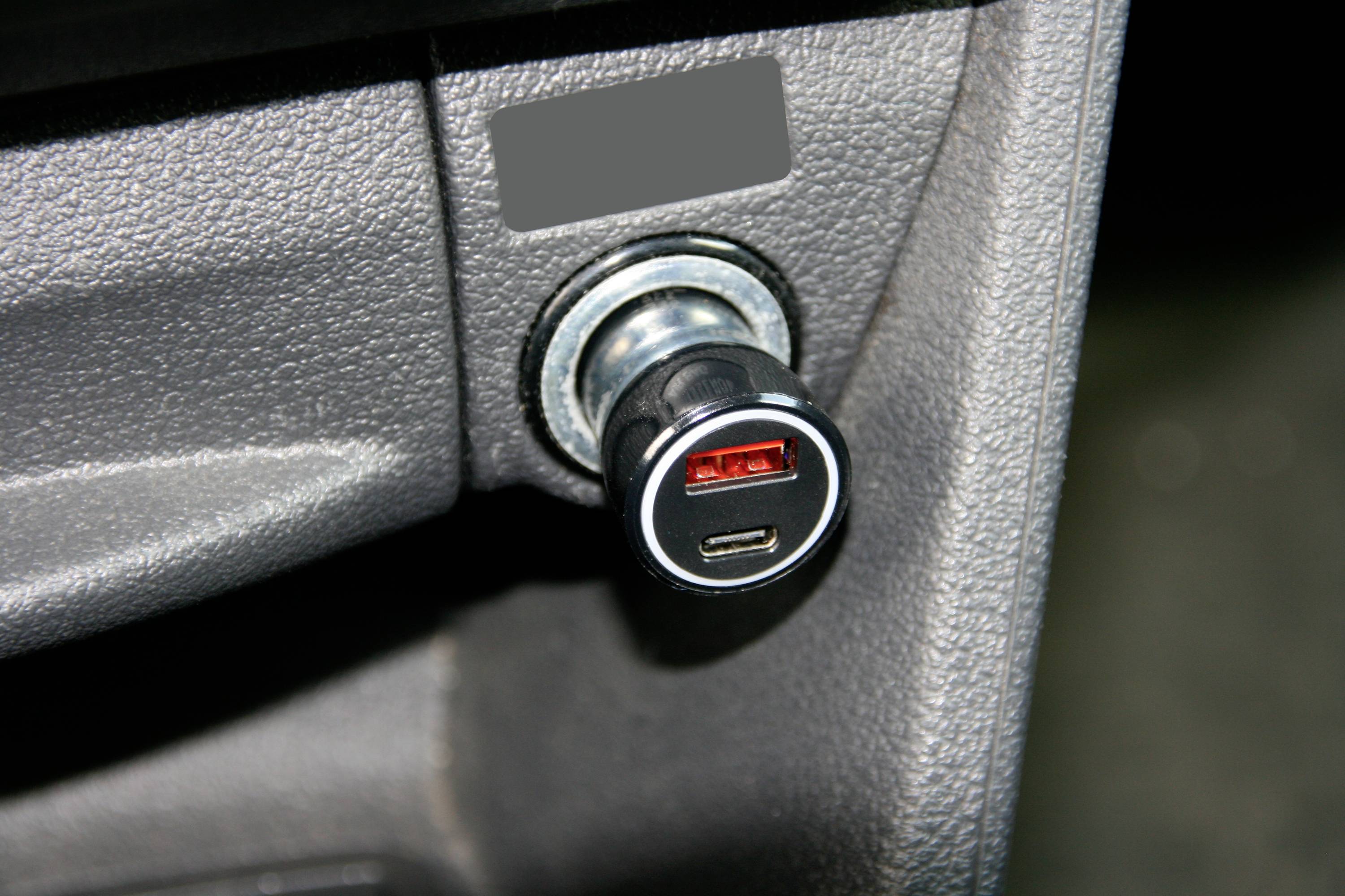 USB-Ladegerät steckt in einem Zigarettenanzünder in einem Auto.