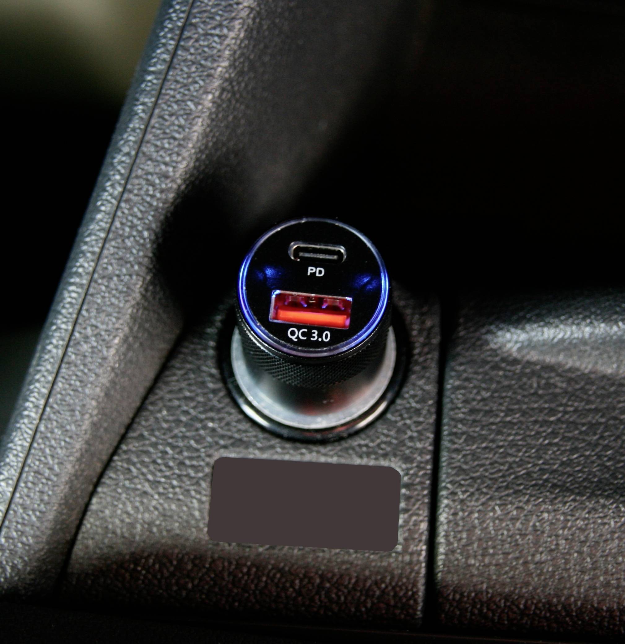Ein Autoadapter mit USB-Anschlüssen, darunter ein roter Anschluss mit der Aufschrift 'QC 3.0' und ein zweiter Anschluss mit der Aufschrift 'PD'.