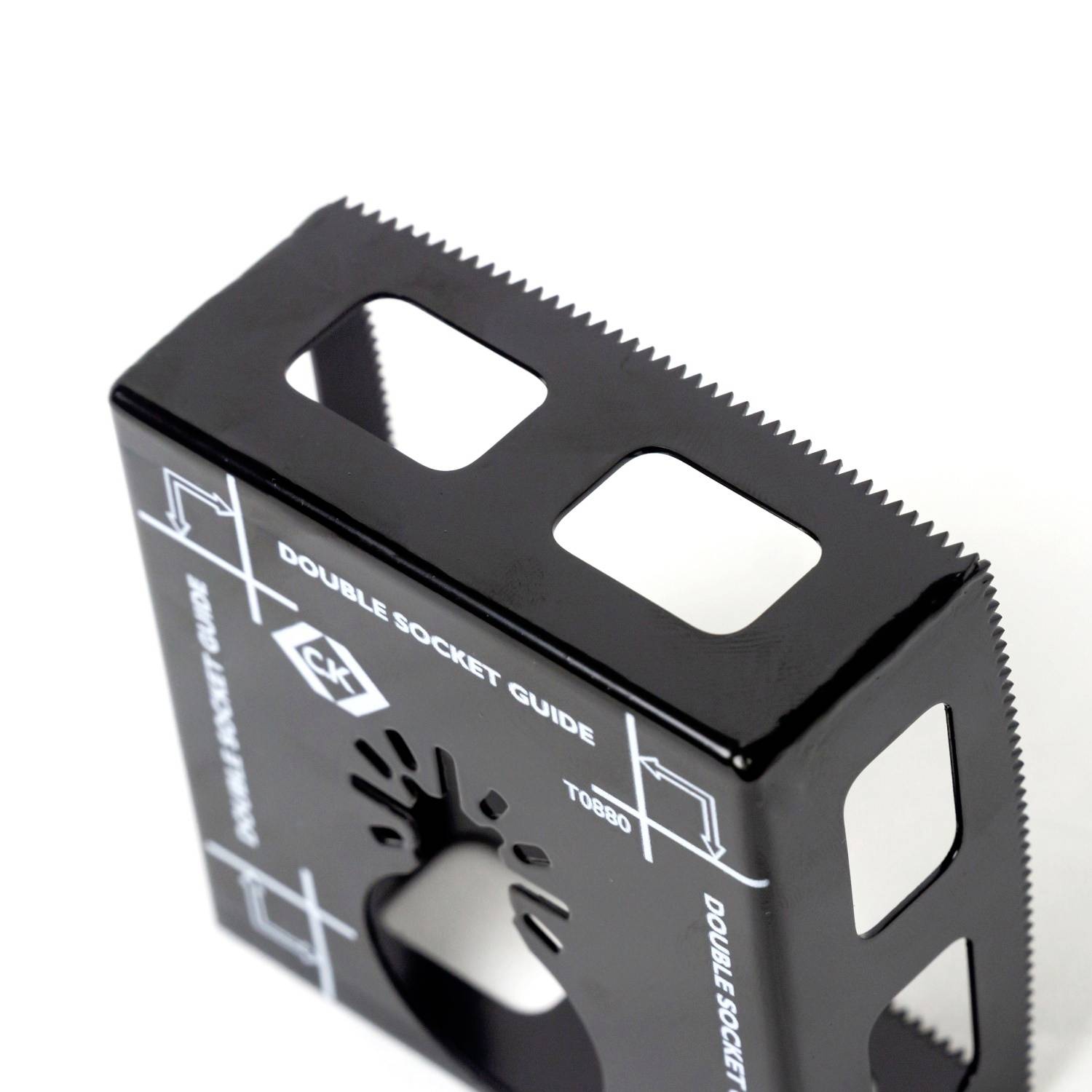 Schwarzes, quadratisches Werkzeug mit gezackten Kanten und ausgeschnittenen Rechtecken. Aufschrift: 'Double Socket Guide'.
